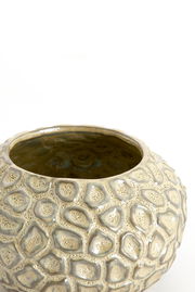 Nahaufnahme eines dekorativen Teelichthalters mit strukturierter, steinartiger Oberfläche in beige und grauen Tönen, von oben betrachtet.