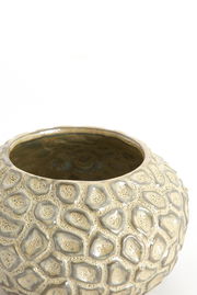 Nahaufnahme eines dekorativen Teelichthalters mit strukturierter, steinartiger Oberfläche in beige und grauen Tönen, von oben betrachtet.