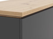 Nahaufnahme eines Highboards mit einer Kombination aus einer glatten, dunklen Oberfläche und einer natürlichen Holzplatte, perspektivisch von der Seite aufgenommen.