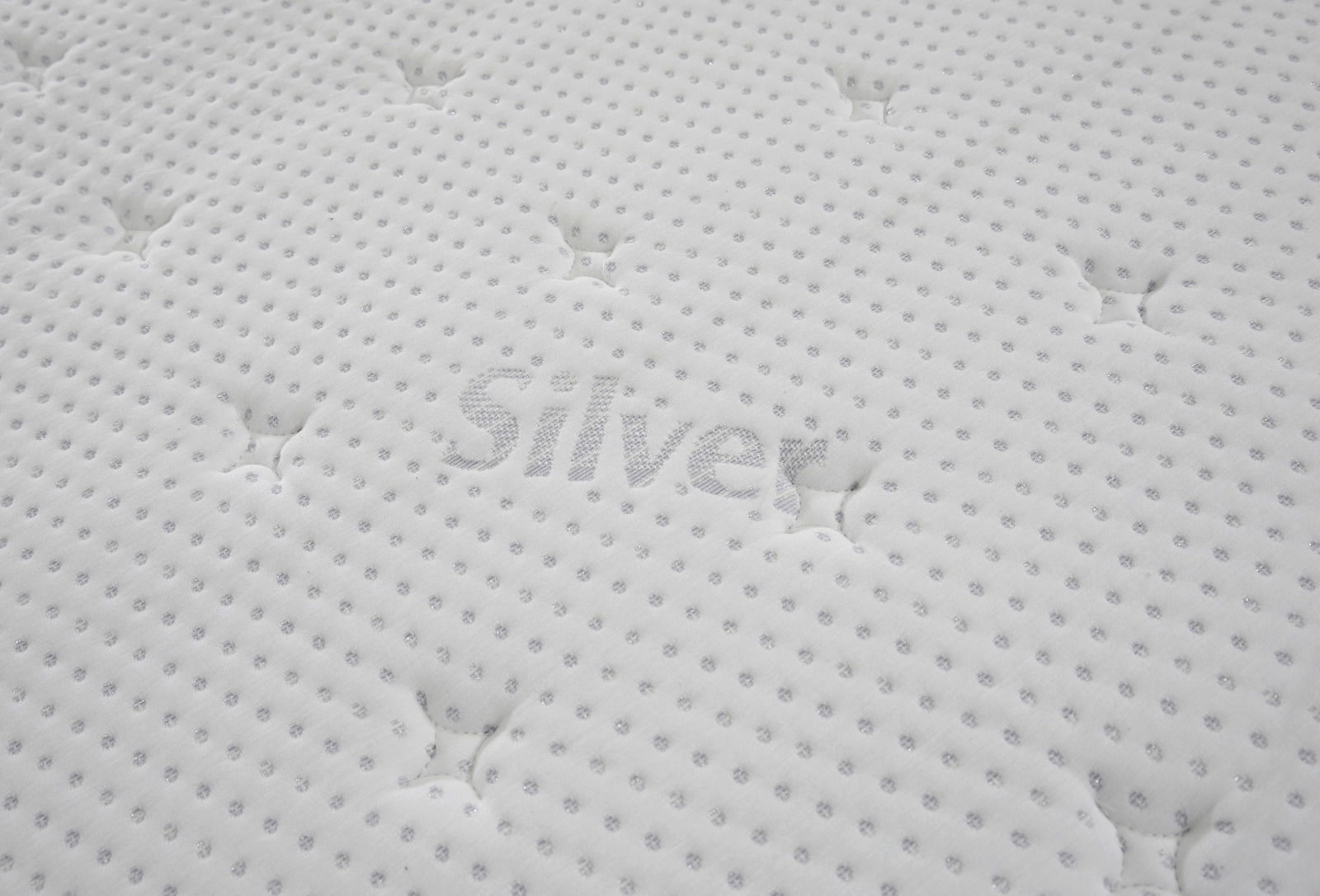 Nahaufnahme einer weißen, gesteppten Matratzenoberfläche mit dem Schriftzug 'Silver'.