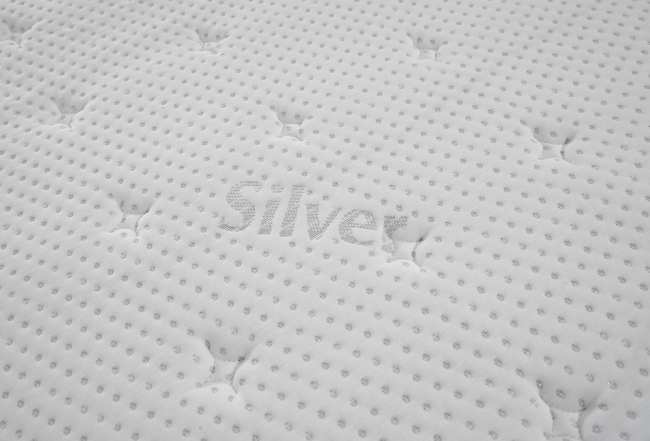 Nahaufnahme einer weißen, gesteppten Matratzenoberfläche mit dem Schriftzug 'Silver'.
