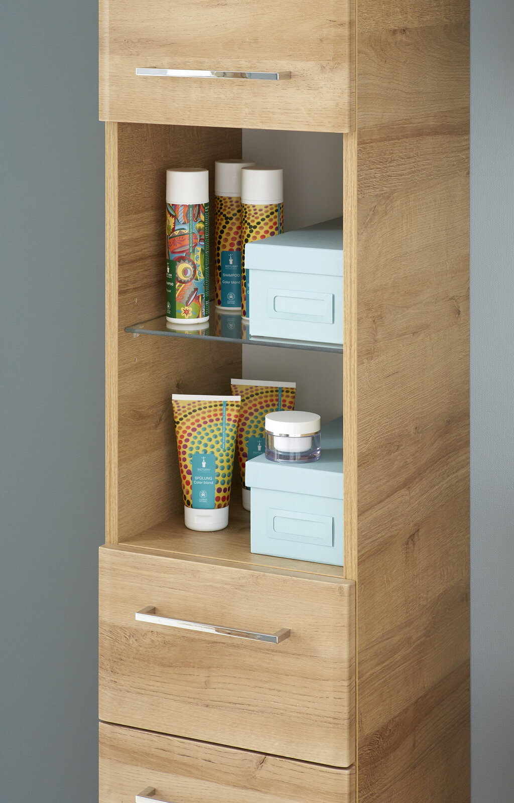 Hochschrank aus Holz mit offenen Regalen, gefüllt mit bunten Flaschen und Boxen, seitliche Perspektive