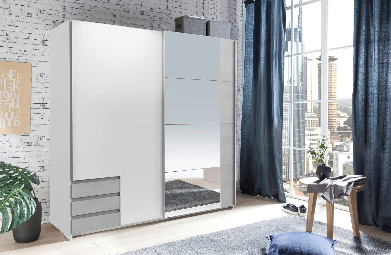 Z2 Schwebetürenschrank 2-türig EMDEN Moderner, zweiflügeliger Schwebetürenschrank in Weiß mit Spiegel, seitliche Perspektive, in einem hellen Raum mit großen Fenstern und urbanem Ausblick.