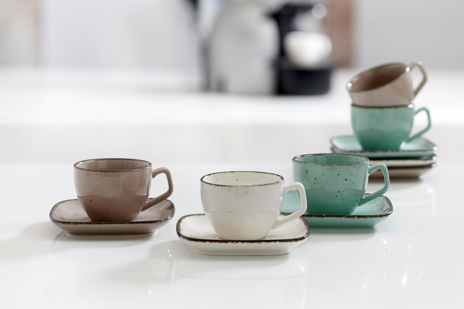 Ritzenhoff & Breker Espressotasse CASA Drei Espressotassen mit Untertassen in verschiedenen Farben (grau, weiß, grün) auf einem Tisch, aus seitlicher Perspektive fotografiert.