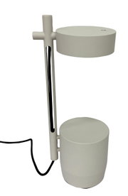 Moderne witte metalen tafellamp met cilindervormige voet en ronde lampenkap, zwart snoer zichtbaar, gefotografeerd in zijaanzicht tegen een witte achtergrond.