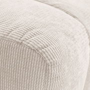 Nahaufnahme eines cremefarbenen Hockers mit gerippter Textur, seitliche Perspektive