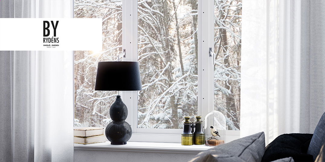 Eine schwarze Lampe auf einer Fensterbank, weiße Vorhänge vor einem verschneiten Wald. Logo 