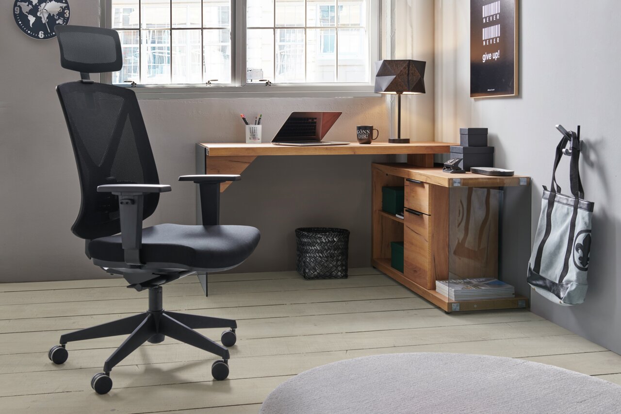 Moderner Eck-Schreibtisch aus Holz in einem stilvollen Büro, mit einem ergonomischen Bürostuhl im Vordergrund. Perspektive von der Seite.