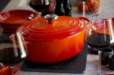 Ofenroter Bräter von Le Creuset, 29 cm, auf einem Tisch mit Weingläsern, seitliche Perspektive