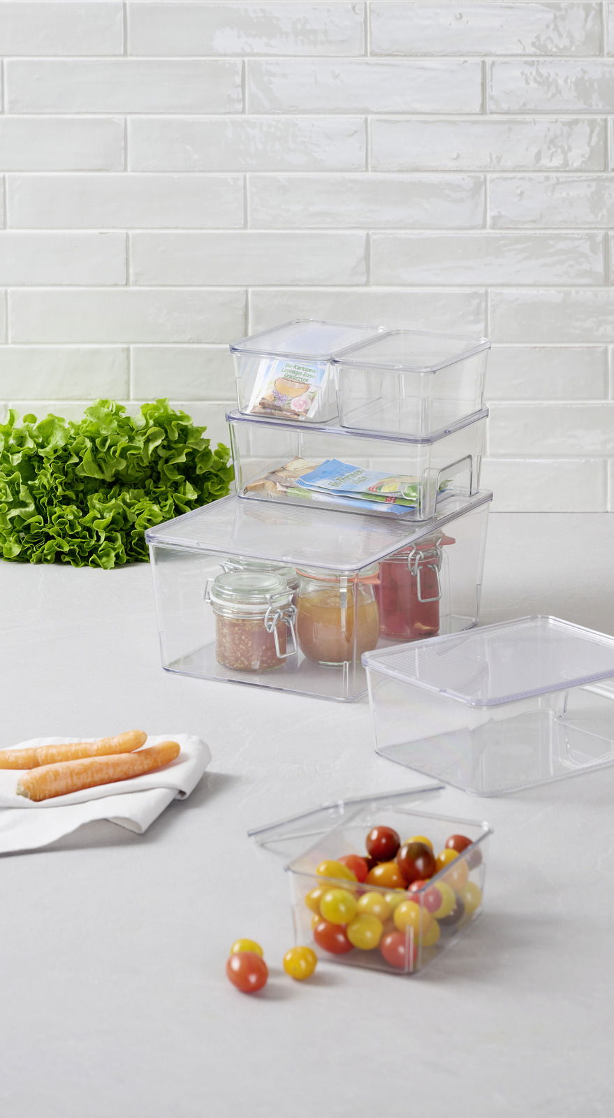 Homeware Organizer 7-tlg Transparente Aufbewahrungsboxen in verschiedenen Größen, gestapelt und gefüllt mit Lebensmitteln, auf einer Küchenarbeitsplatte. Perspektive von vorne.