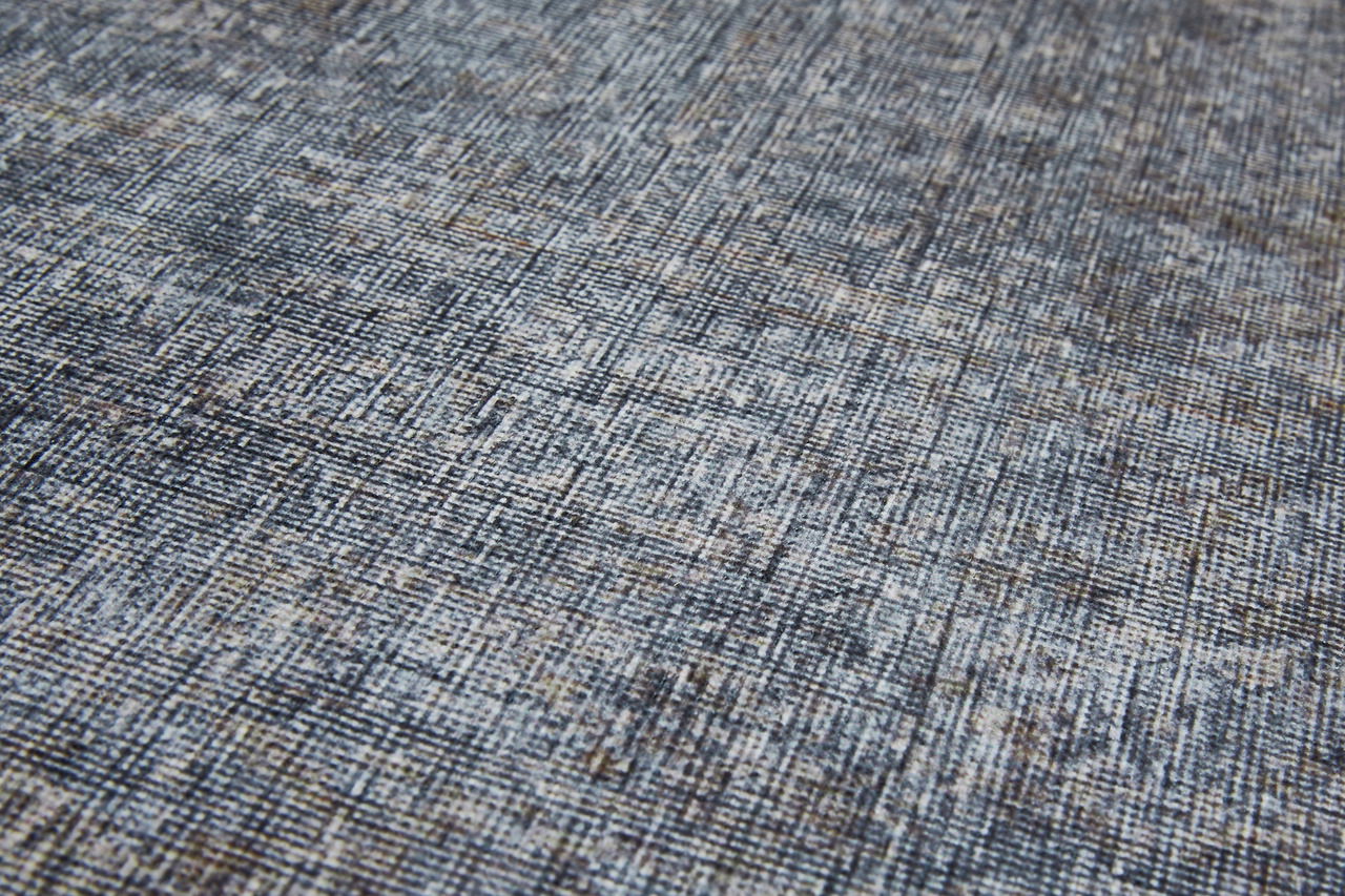 Nahaufnahme eines Teppichs mit einem modernen, abstrakten Muster in Grautönen, schräg von der Seite fotografiert.