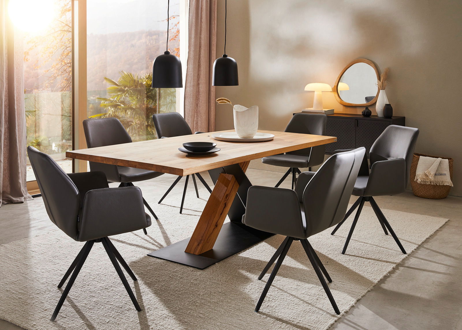 Moderner Esstisch aus Holz mit schrägem Metallgestell, umgeben von sechs grauen Stühlen in einem stilvoll eingerichteten Raum mit Blick auf die Natur durch große Fenster.