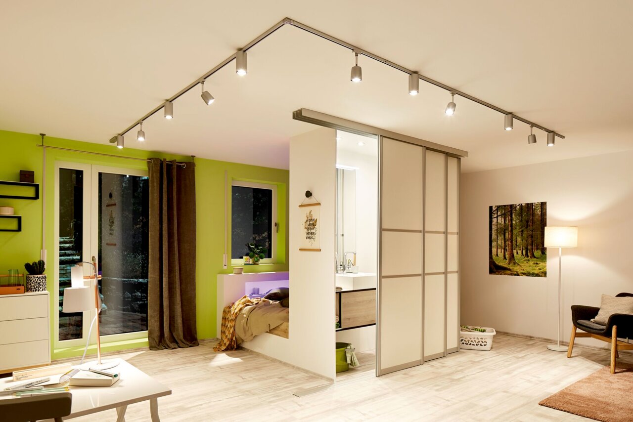 Moderne LED-Schienenbeleuchtung in einem stilvollen Wohnzimmer mit grüner Wand und Schiebetür, Perspektive von unten.