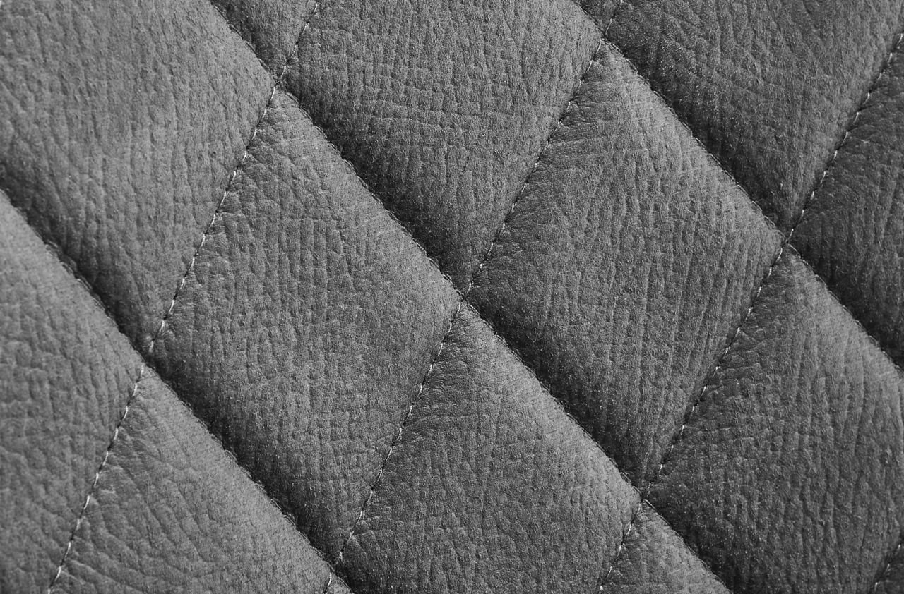 Nahaufnahme einer grauen, gesteppten Lederoberfläche eines Drehstuhls.