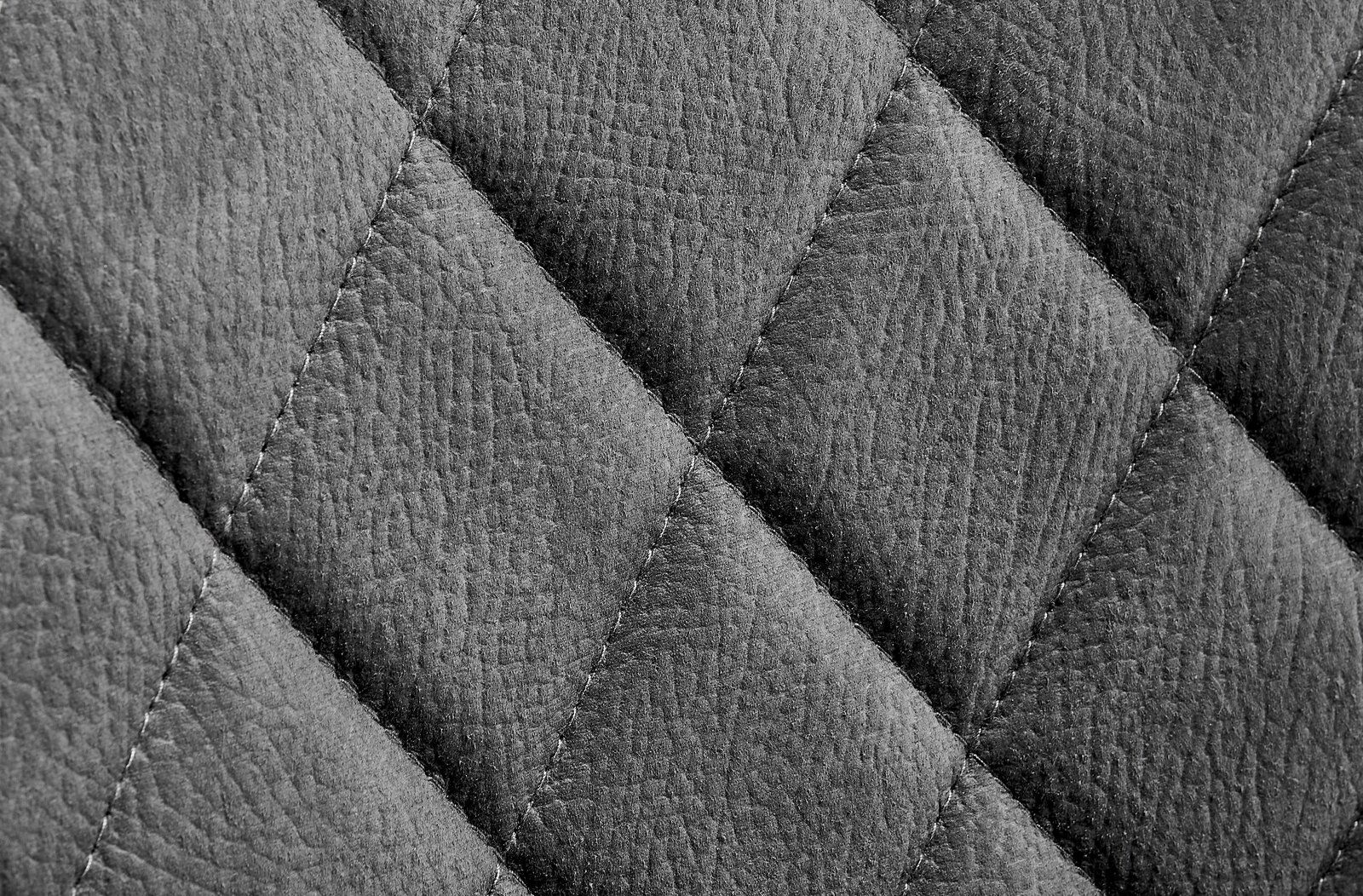 Nahaufnahme einer grauen, gesteppten Lederoberfläche eines Drehstuhls.