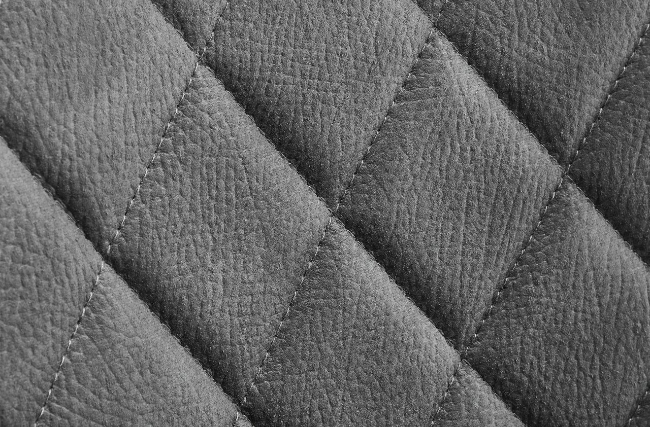 Nahaufnahme einer grauen, gesteppten Lederoberfläche eines Drehstuhls.