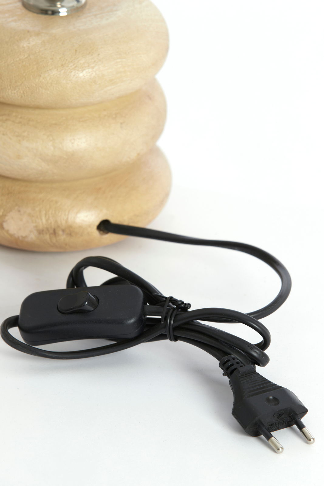 Nahaufnahme eines Lampenfußes aus Holz mit einem schwarzen Kabel und Schalter, seitliche Perspektive.