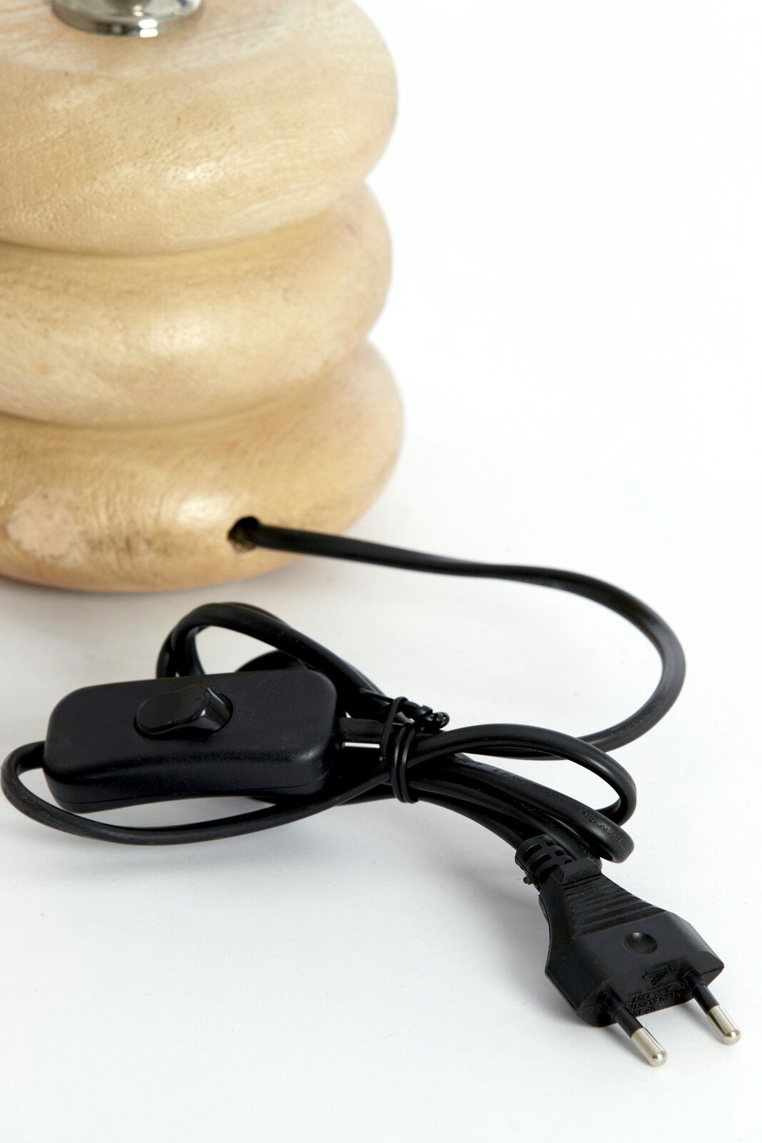 Nahaufnahme eines Lampenfußes aus Holz mit einem schwarzen Kabel und Schalter, seitliche Perspektive.