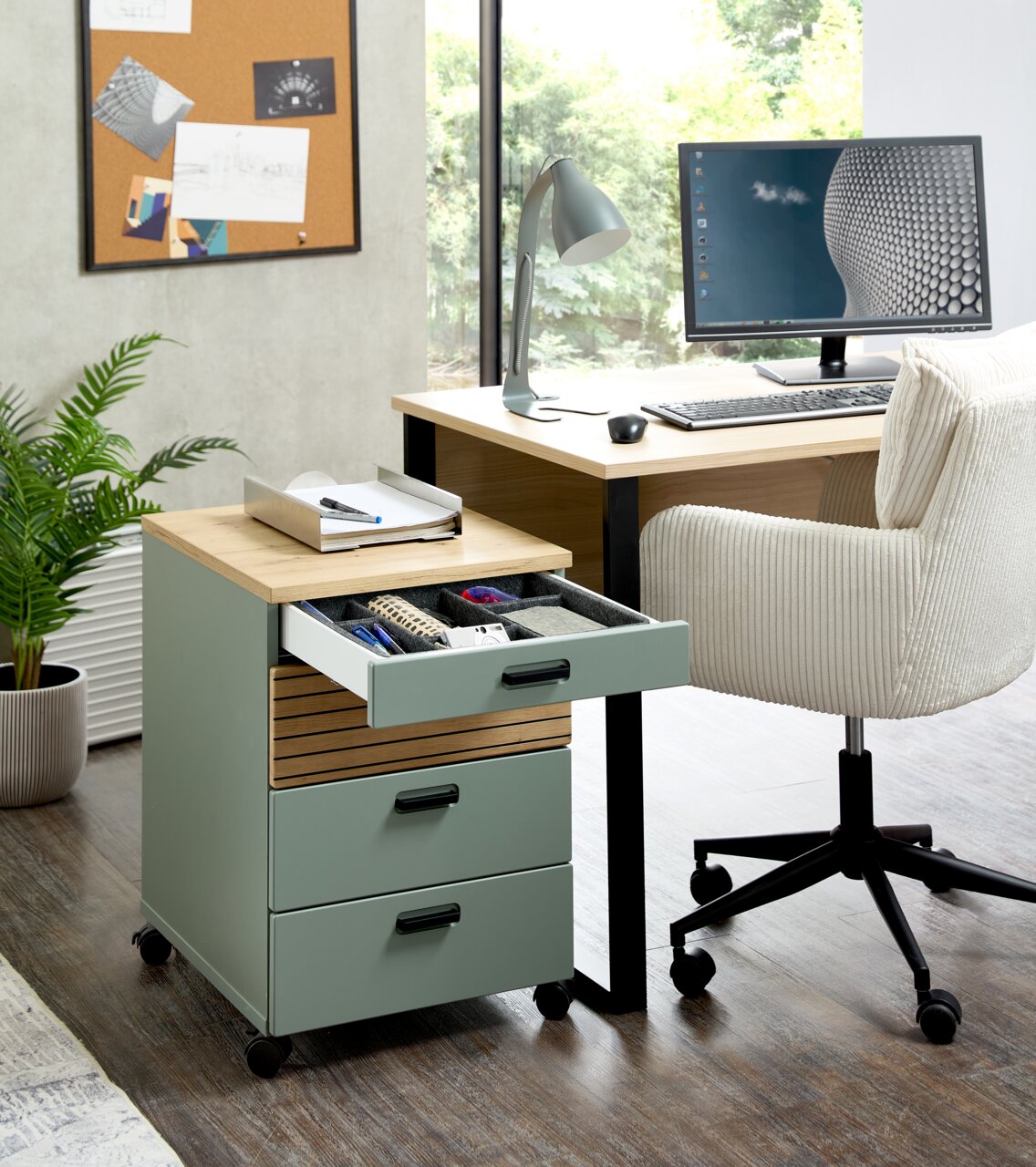 Rollcontainer mit drei Schubladen, teilweise geöffnet, in einem modernen Büro mit Schreibtisch und Stuhl, seitliche Perspektive