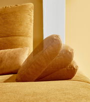 Nahaufnahme einer gelben Rundecke mit weichem Stoffbezug, seitliche Perspektive