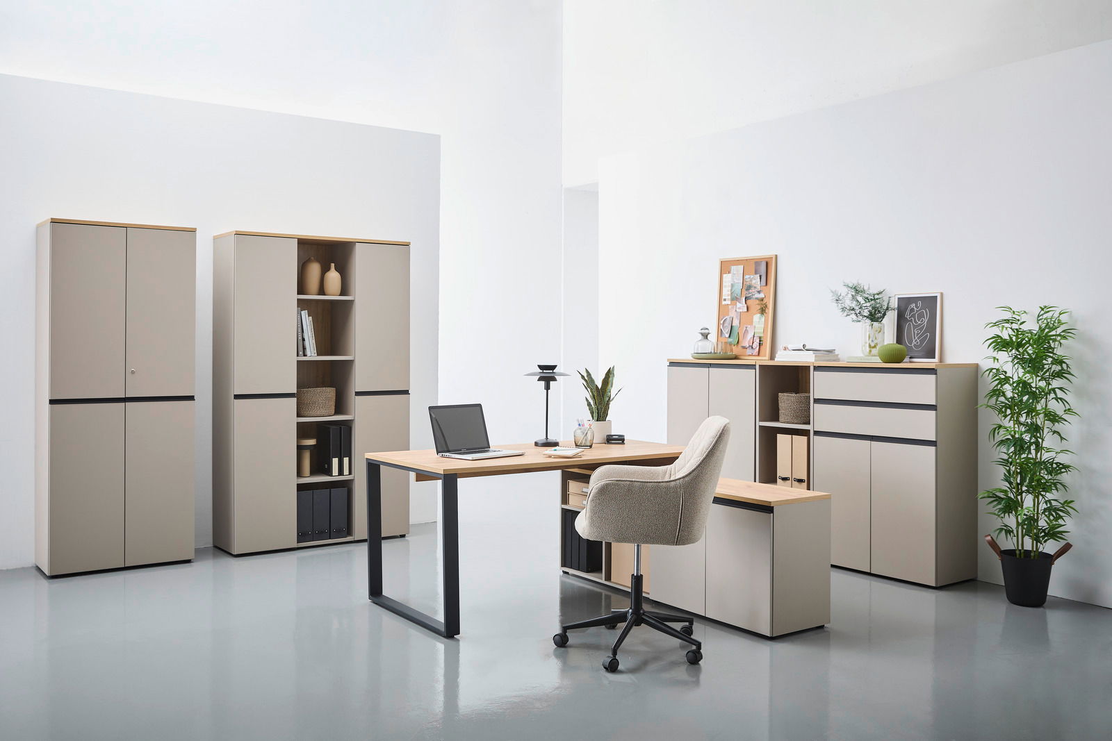 Moderne Büromöbel in einem hellen Raum, bestehend aus einem Winkelschreibtisch mit Laptop, mehreren Aktenschränken und einem Rollcontainer. Die Perspektive zeigt die Möbel von vorne.