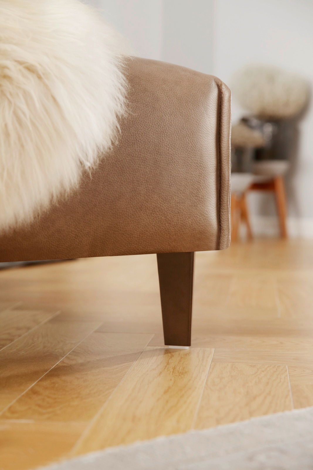 Nahaufnahme einer braunen Polsterrundecke mit Holzbein, seitliche Perspektive