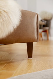 Nahaufnahme einer braunen Polsterrundecke mit Holzbein, seitliche Perspektive