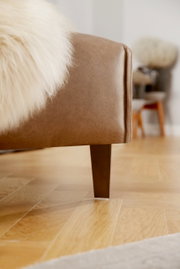 Nahaufnahme einer braunen Polsterrundecke mit Holzbein, seitliche Perspektive