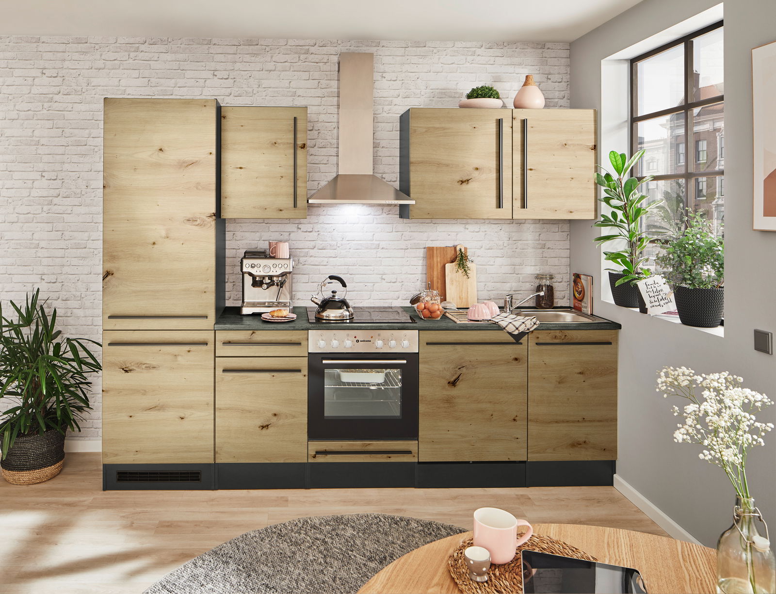 Moderne Küchenzeile in Holzoptik mit Elektrogeräten, Pflanzen und Dekorationen, aus der Perspektive eines Esszimmers betrachtet.