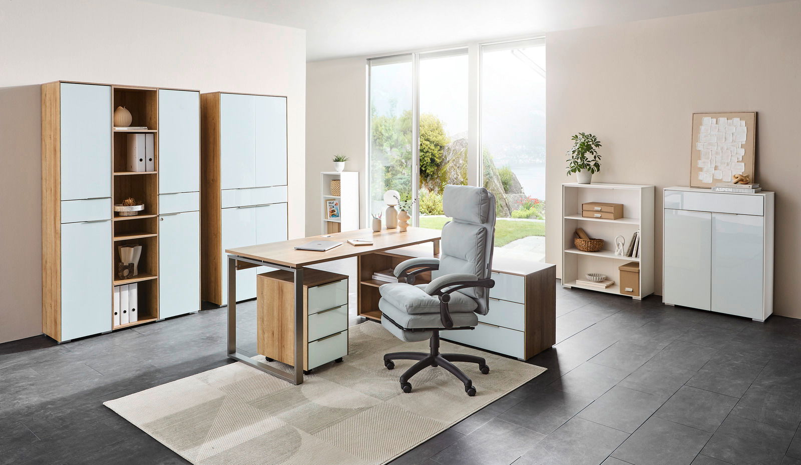 Moderne Büroumgebung mit Eckschreibtisch NEVADA, Aktenschränken und Rollcontainer in heller Holzoptik und weißen Fronten, seitliche Perspektive.