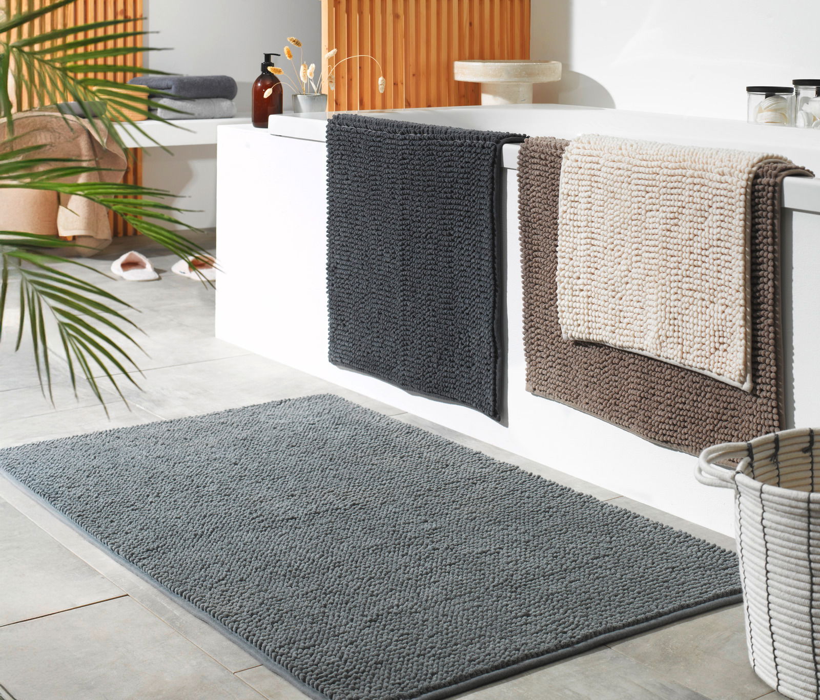 Badezimmer mit mehreren Badteppichen in verschiedenen Farben und Größen, Perspektive von schräg oben.