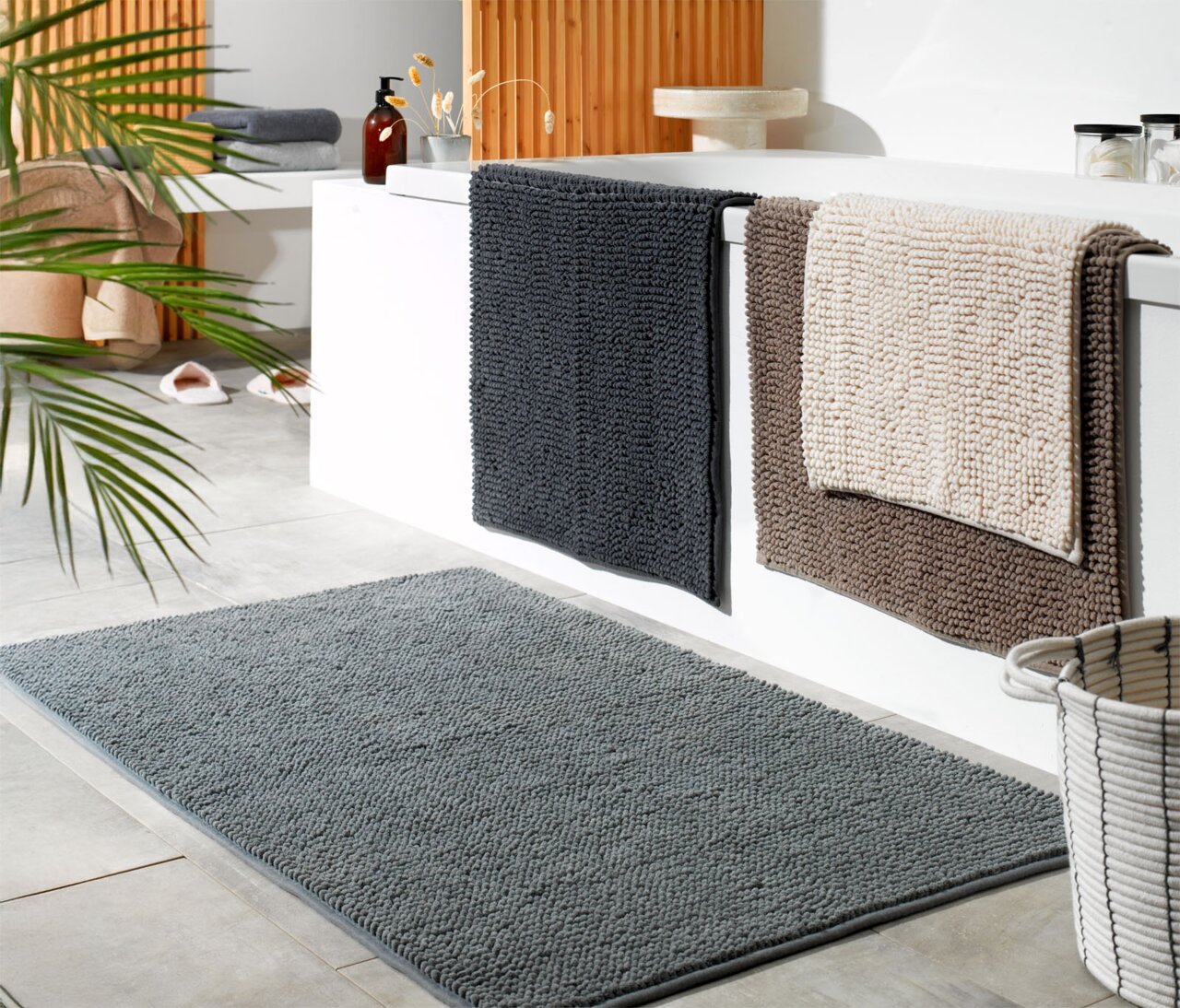 Badezimmer mit mehreren Badteppichen in verschiedenen Farben und Größen, Perspektive von schräg oben.