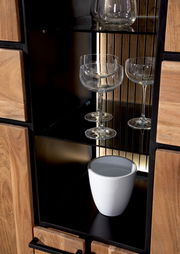 Nahaufnahme eines Highboards mit Glastüren, das Gläser und eine weiße Vase zeigt, aus einer frontalen Perspektive.