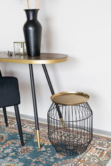 Moderner Beistelltisch mit goldenem Tablett und schwarzem Drahtgestell, seitliche Perspektive.