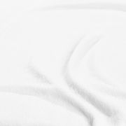 Nahaufnahme eines weißen Spannbetttuchs mit weicher Textur, leicht gefaltet.