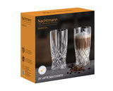 Verpackung des Barista Latte Macchiato SET/2 von Nachtmann mit zwei Kristallgläsern, eines leer und eines mit Latte Macchiato gefüllt, auf einer dunklen Oberfläche mit Kaffeebohnen, seitliche Perspektive.