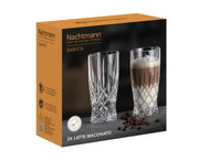 Verpakking van de Barista Latte Macchiato SET/2 van Nachtmann met twee kristallen glazen, één leeg en één gevuld met latte macchiato, op een donkere ondergrond met koffiebonen, zijaanzicht.