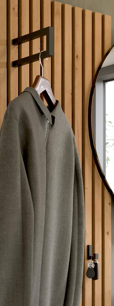 Garderobenpaneel aus Holz mit Haken, an dem ein Mantel hängt. Seitliche Perspektive mit einem Spiegel im Hintergrund.