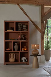 Vase in einem modernen Regal, seitliche Perspektive, umgeben von dekorativen Objekten in einem rustikalen Raum.