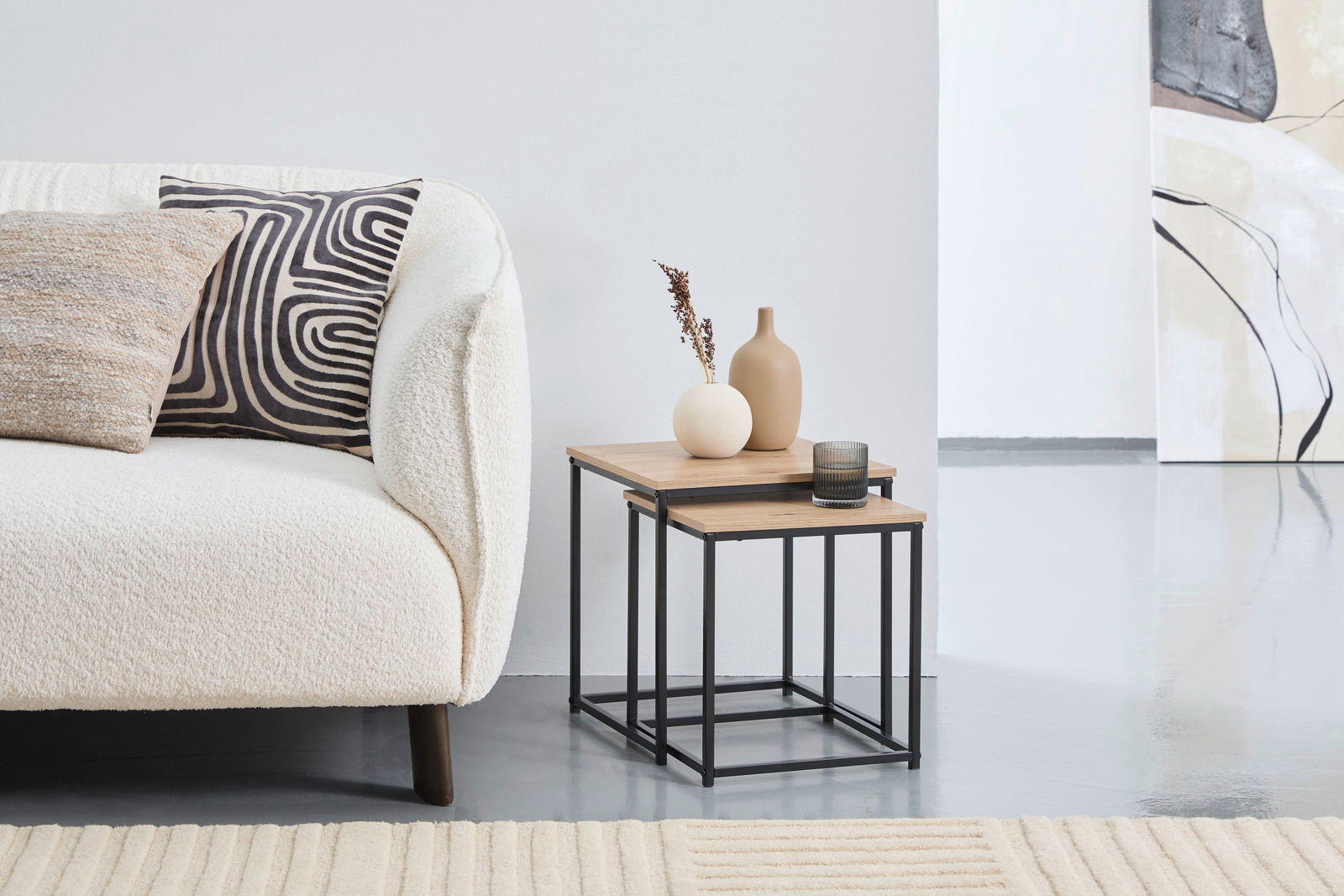 Beistelltisch-Set LINA aus Holz und Metall, bestehend aus zwei ineinander verschachtelten Tischen, seitliche Perspektive neben einem Sofa.