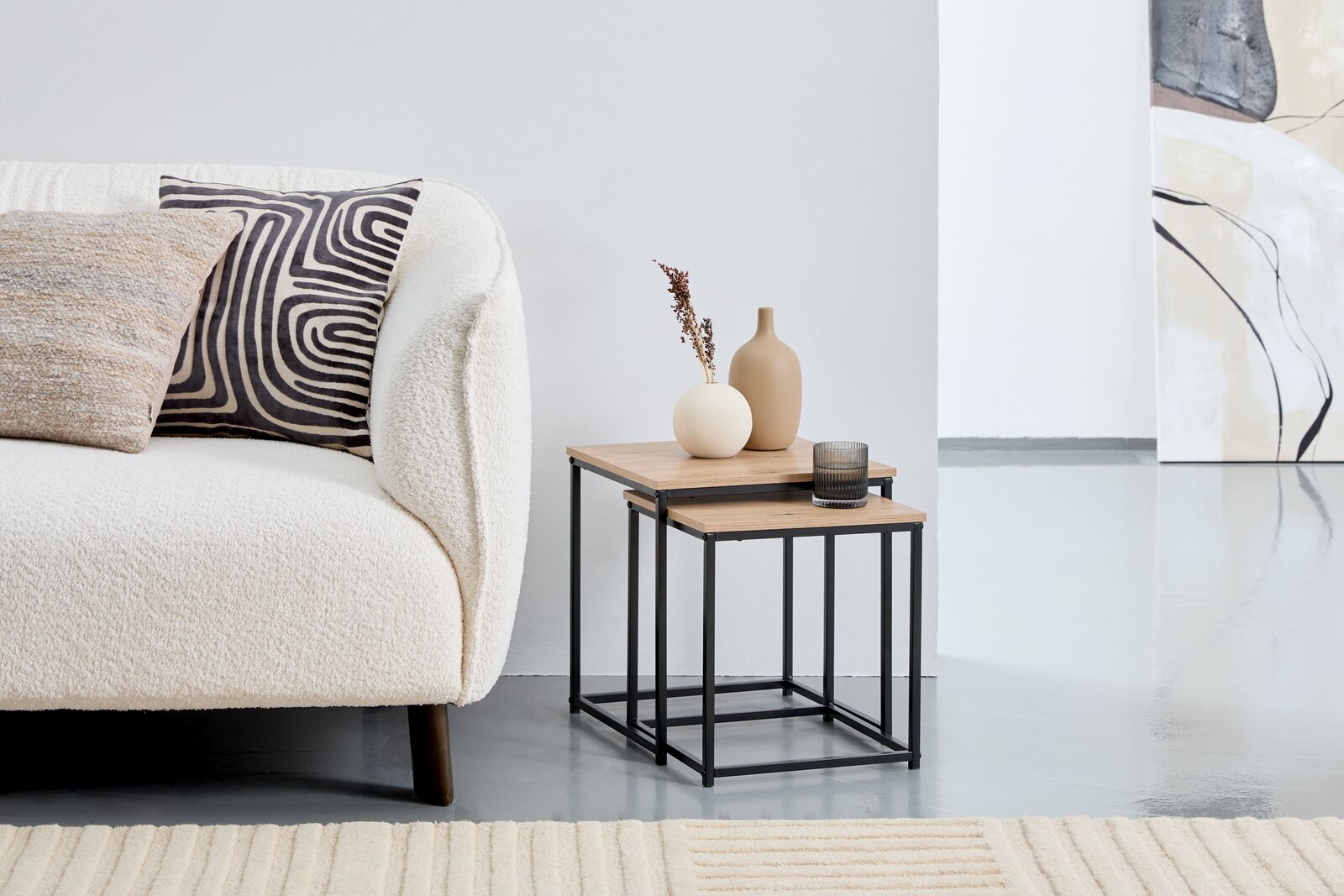 Beistelltisch-Set LINA aus Holz und Metall, bestehend aus zwei ineinander verschachtelten Tischen, seitliche Perspektive neben einem Sofa.