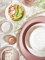 Porzellan-Set Valencia 30tlg. aus der Vogelperspektive, bestehend aus dekorativen Tellern und Schalen mit feinem Muster, arrangiert mit Avocado, Kichererbsen und Radieschen.