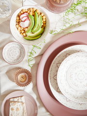 Porzellan-Set Valencia 30tlg. aus der Vogelperspektive, bestehend aus dekorativen Tellern und Schalen mit feinem Muster, arrangiert mit Avocado, Kichererbsen und Radieschen.