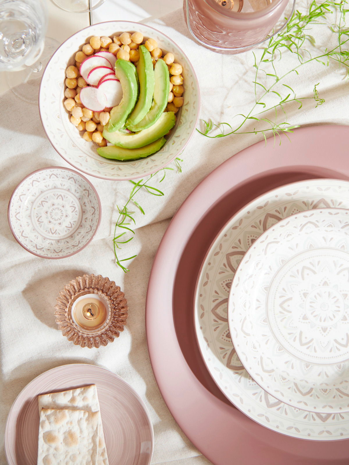 Porzellan-Set Valencia 30tlg. aus der Vogelperspektive, bestehend aus dekorativen Tellern und Schalen mit feinem Muster, arrangiert mit Avocado, Kichererbsen und Radieschen.