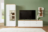 Moderne Wandkombination in Weiß mit Holzdetails, bestehend aus einem hohen Schrank mit Glastüren, einem breiten TV-Schrank und einem Wandregal mit Dekorationen, frontal betrachtet.