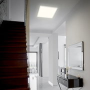 Moderne led-plafondlamp in een elegante, lichte woonkamer, van onderaf gezien.