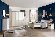 Helles Schlafzimmer mit einem 5-türigen Drehtürenschrank CAMRON, Bett und Kommode in einem modernen, gemütlichen Design. Perspektive: Frontalansicht des Schranks.