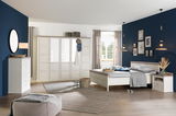 Helles Schlafzimmer mit einem 5-türigen Drehtürenschrank CAMRON, Bett und Kommode in einem modernen, gemütlichen Design. Perspektive: Frontalansicht des Schranks.