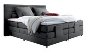 Graues Boxspringbett mit Kopfteil, seitliche Perspektive, dekoriert mit Kissen und Decken.