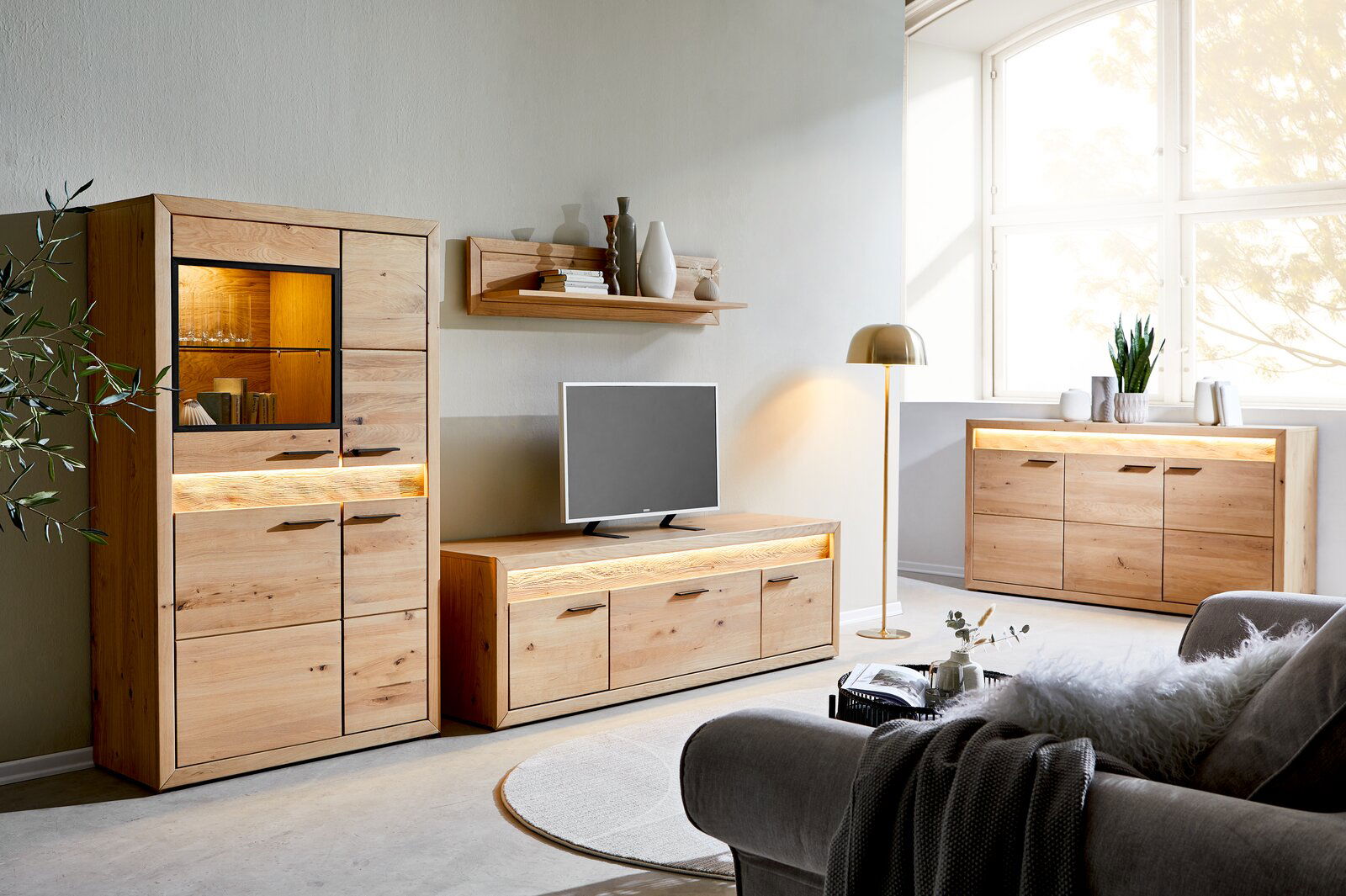 Cantus Sideboard CLEVELAND Wohnzimmer mit modernen Holzmöbeln, darunter ein Highboard, ein Lowboard und ein Sideboard, alle mit Beleuchtung. Perspektive von vorne links.